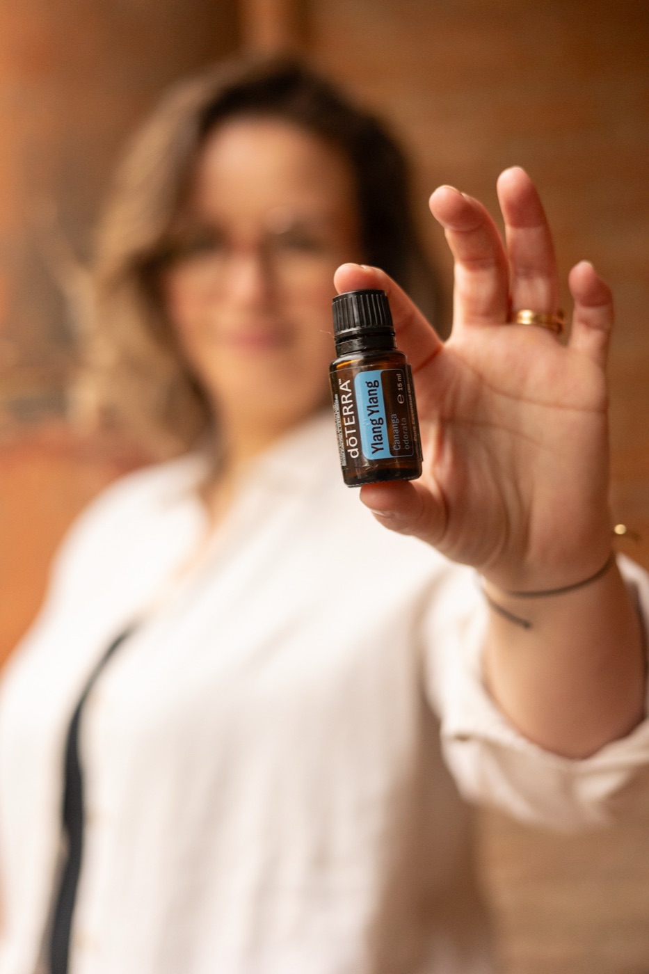 Émilie tend un flacon d’Ylang Ylang dōTERRA